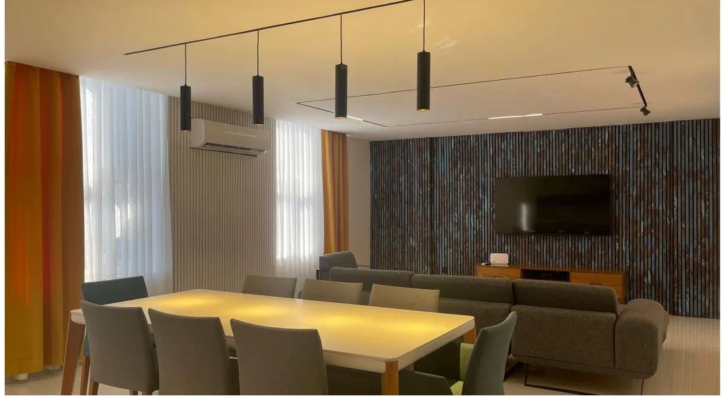 The completed Bandar Abbas living and dining space, with a slatted timber feature wall, layered lighting and finished furnishings photographed after handover.