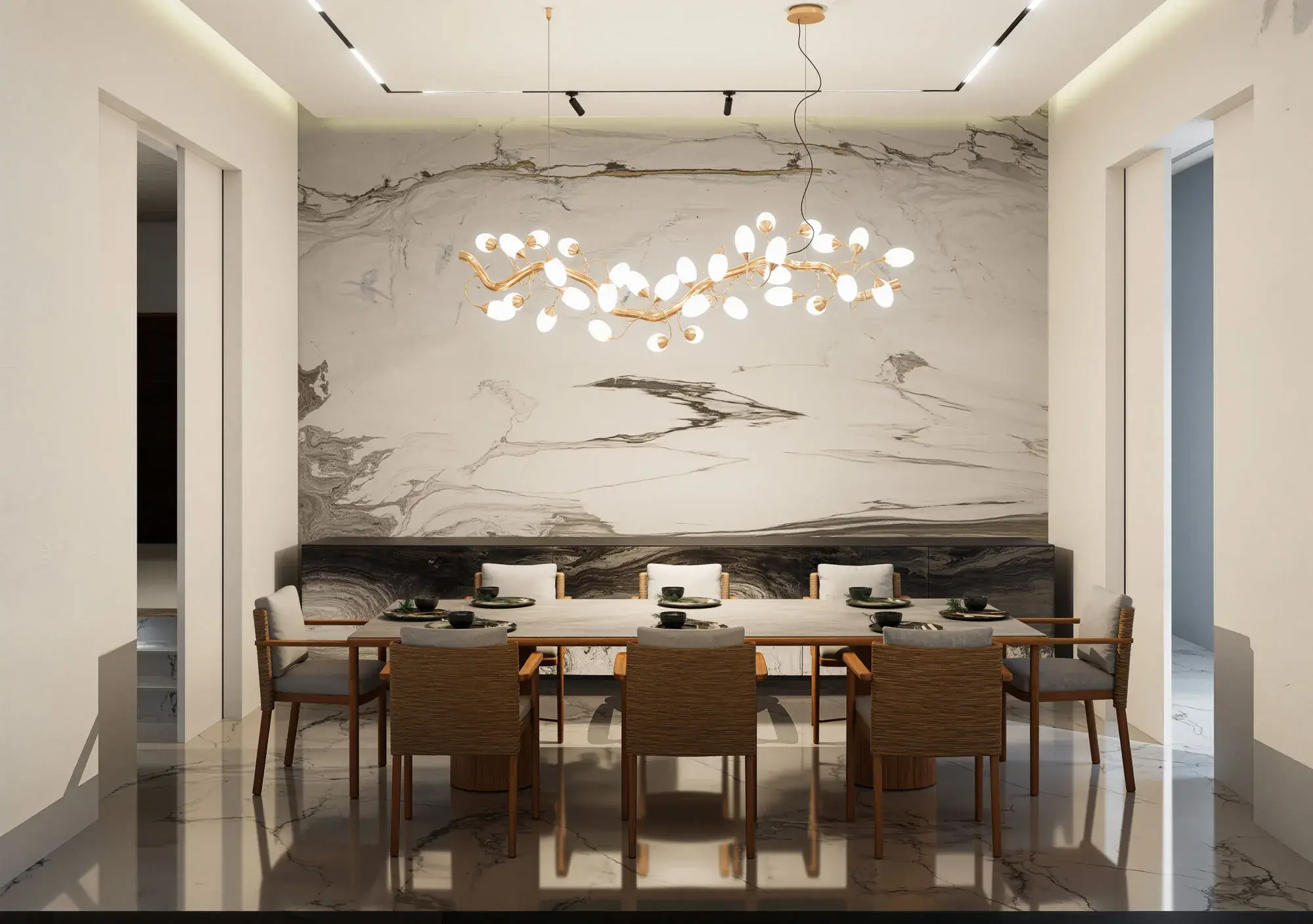 Dining room with a book-matched marble feature wall, a branching brass and opal-glass chandelier over a long timber table, woven dining chairs and polished marble flooring.