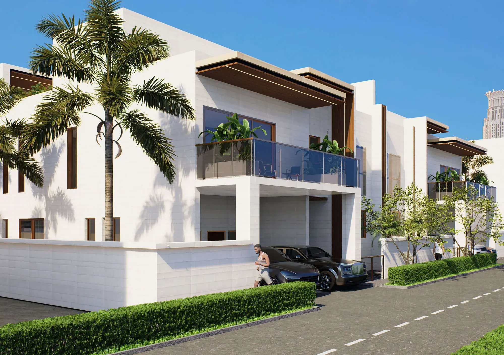 The villas seen from the street by day: a corner unit with a planted balcony above the carport, cars parked beneath, and a clipped hedge running the length of the plot.