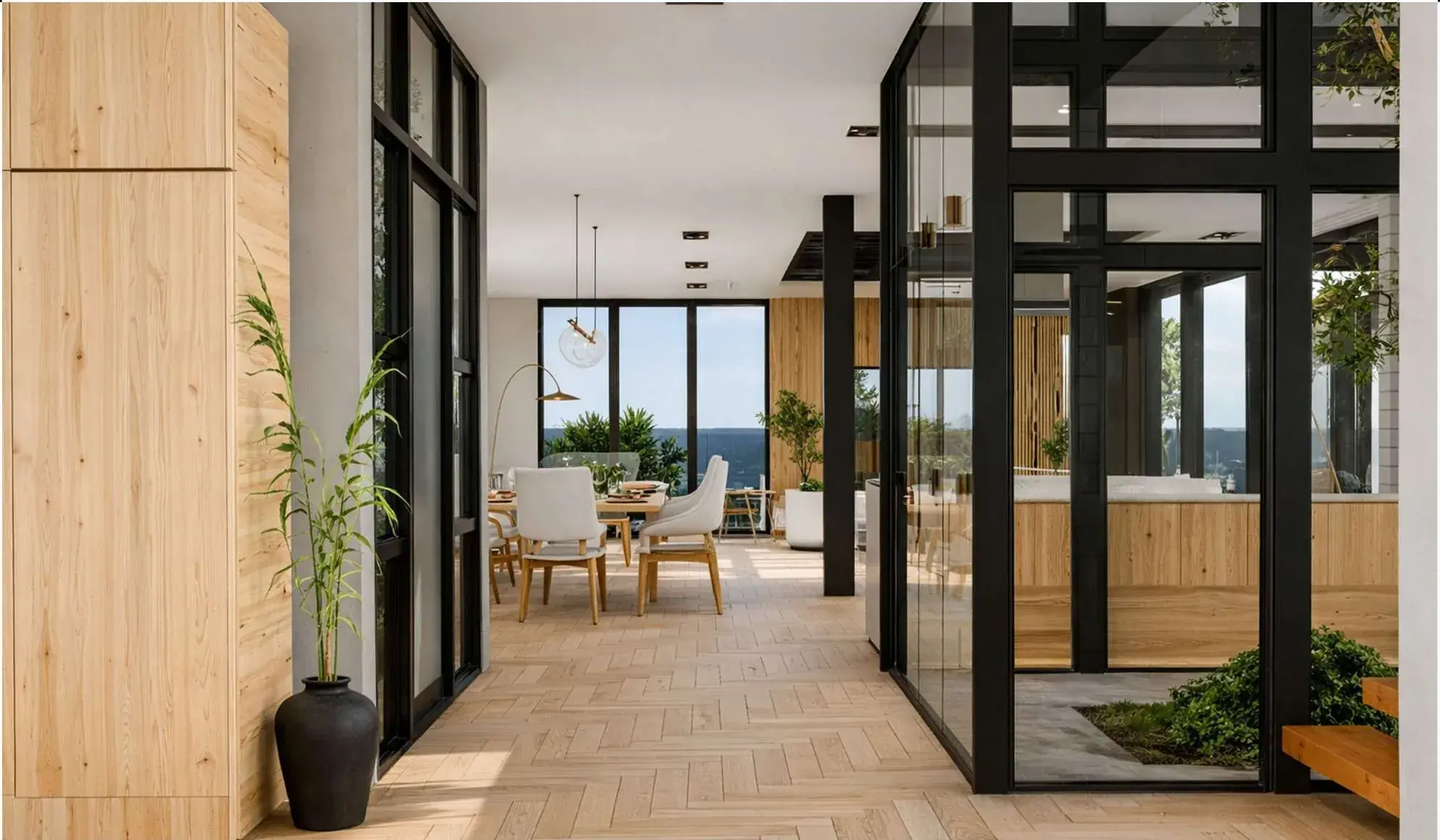 Interior circulation: herringbone oak flooring between black steel-framed glazing, an internal planted courtyard and a dining space beyond with a sea view.