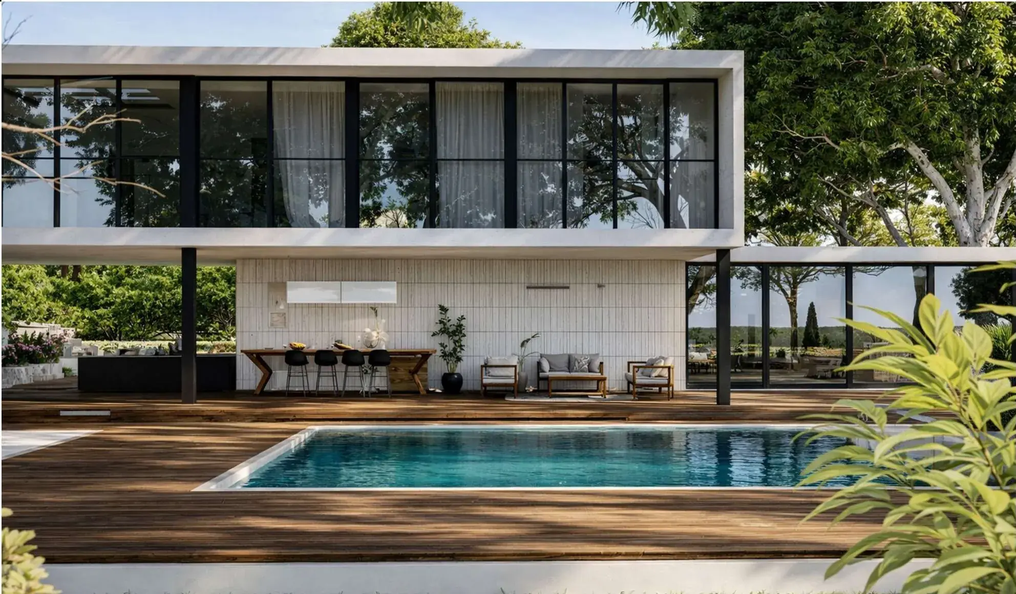 The pool terrace: a glazed upper volume oversailing an outdoor kitchen and seating, timber decking, mature trees and a turquoise lap pool.